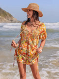 Woman in a colorful dress and straw hat standing on a beach.