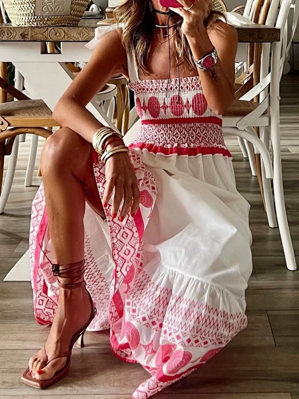 Woman sitting on a chair wearing a pink and white patterned dress.