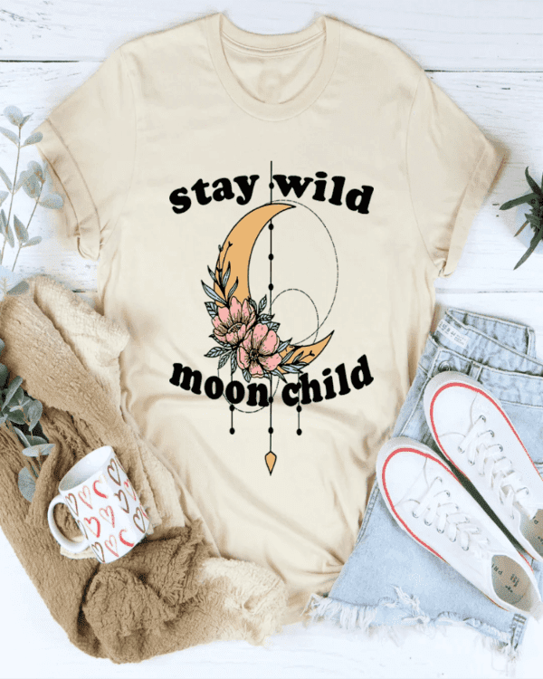 Beige t-shirt with 'stay wild moon child' design, mug, sweater, and jeans on a white background