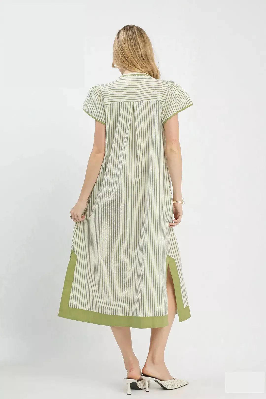 Woman wearing a green and white striped dress on a white background