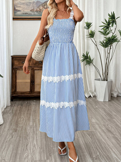Woman wearing a blue and white striped dress with floral details in a room.