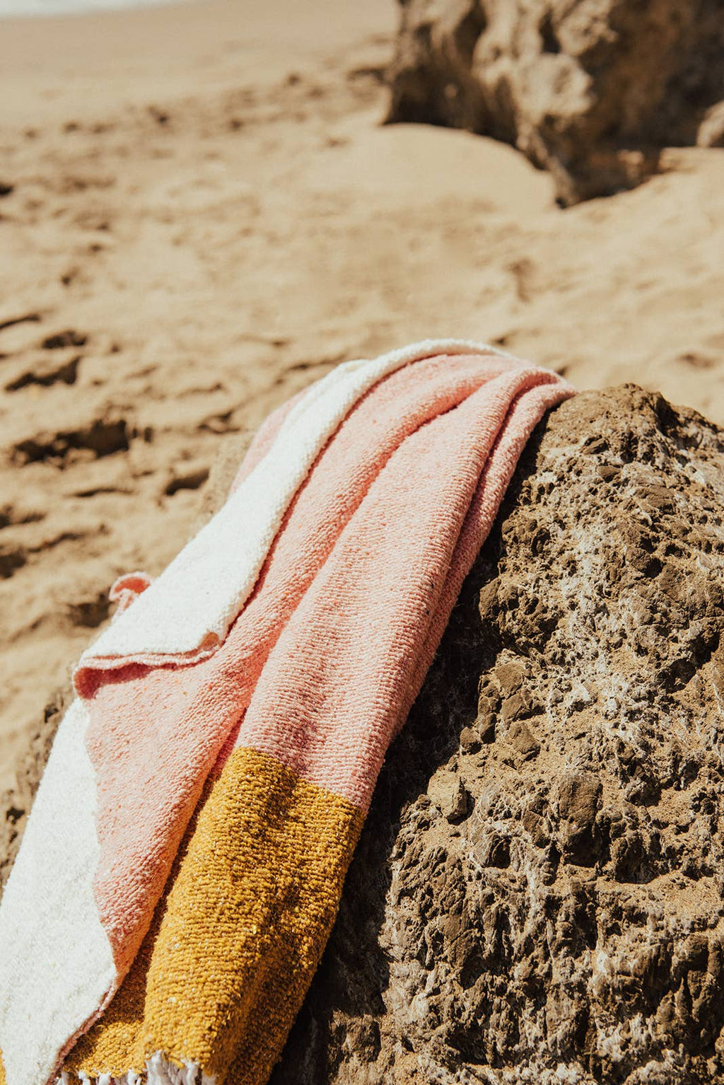 Colorful towel draped over a rock on a sandy beach