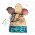 Sustainable soap cake set with natural loofah, bath bomb, and drawstring bag on a white background.