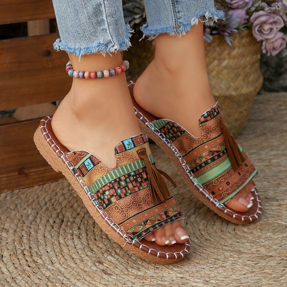Colorful sandals with patterned sole worn by a person on a woven surface.