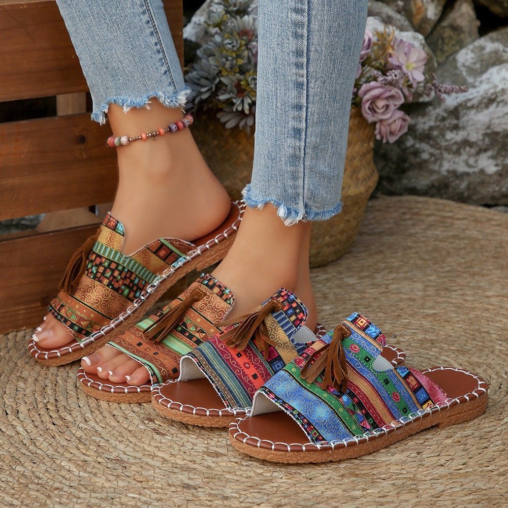 Colorful sandals worn with light blue jeans on a woven surface.