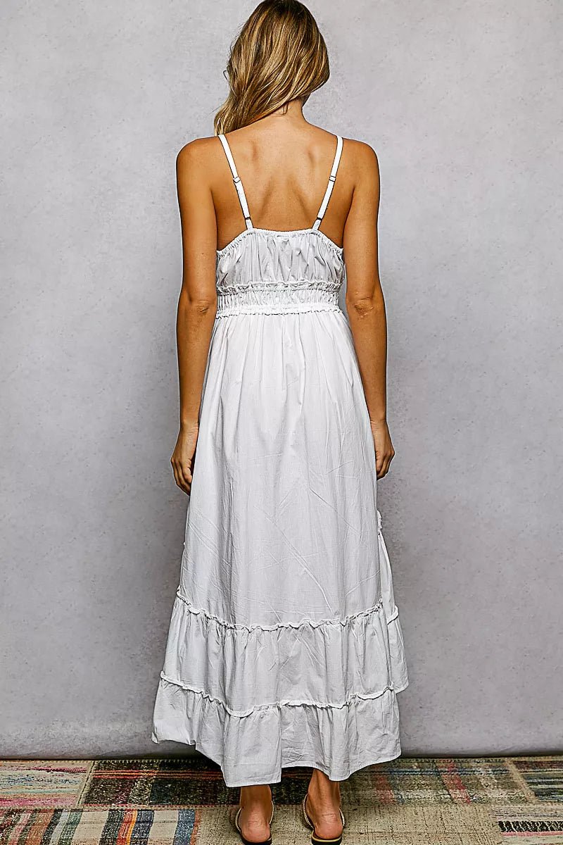 Woman wearing a white dress with thin straps against a plain background