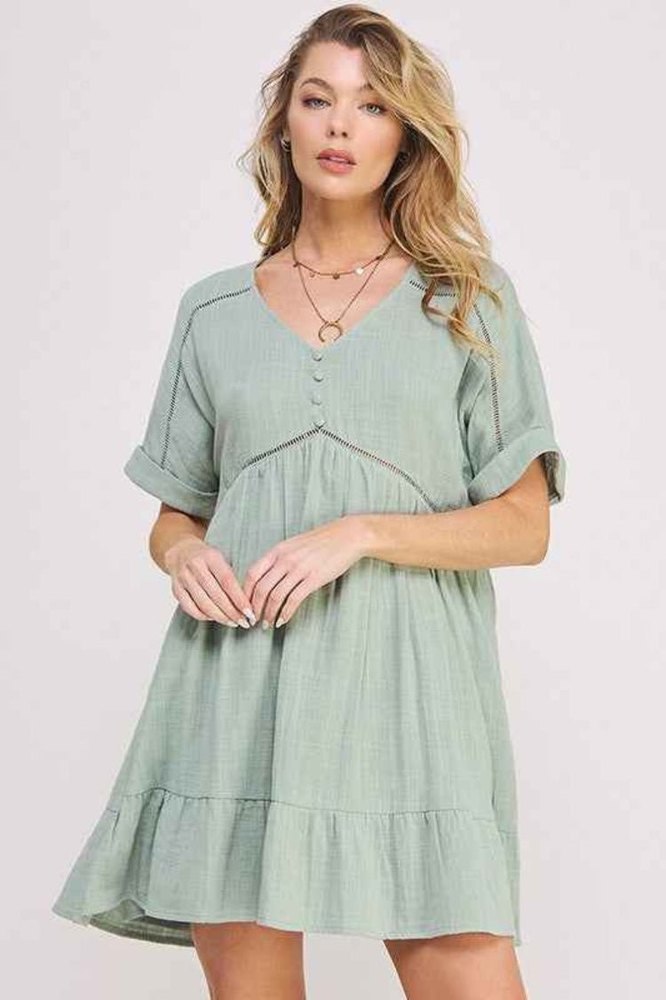 Blonde woman wearing a light green dress with a plain background