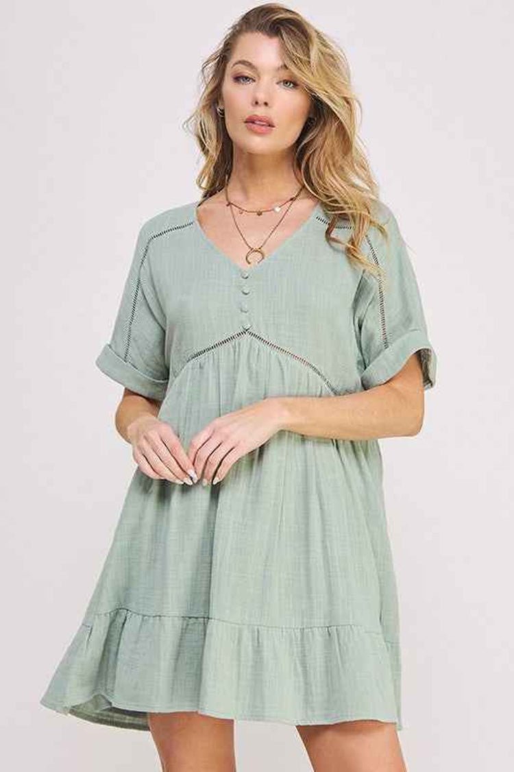 Blonde woman wearing a light green dress with a plain background