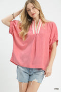 Woman wearing a pink blouse with lace details and denim shorts on a white background