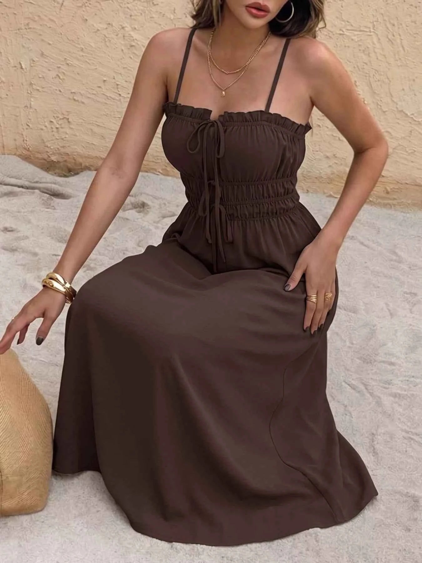Woman wearing a brown dress sitting on a textured surface with a neutral background