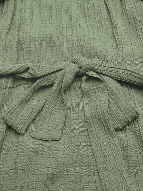 Close-up of a green textured garment with a tie detail.