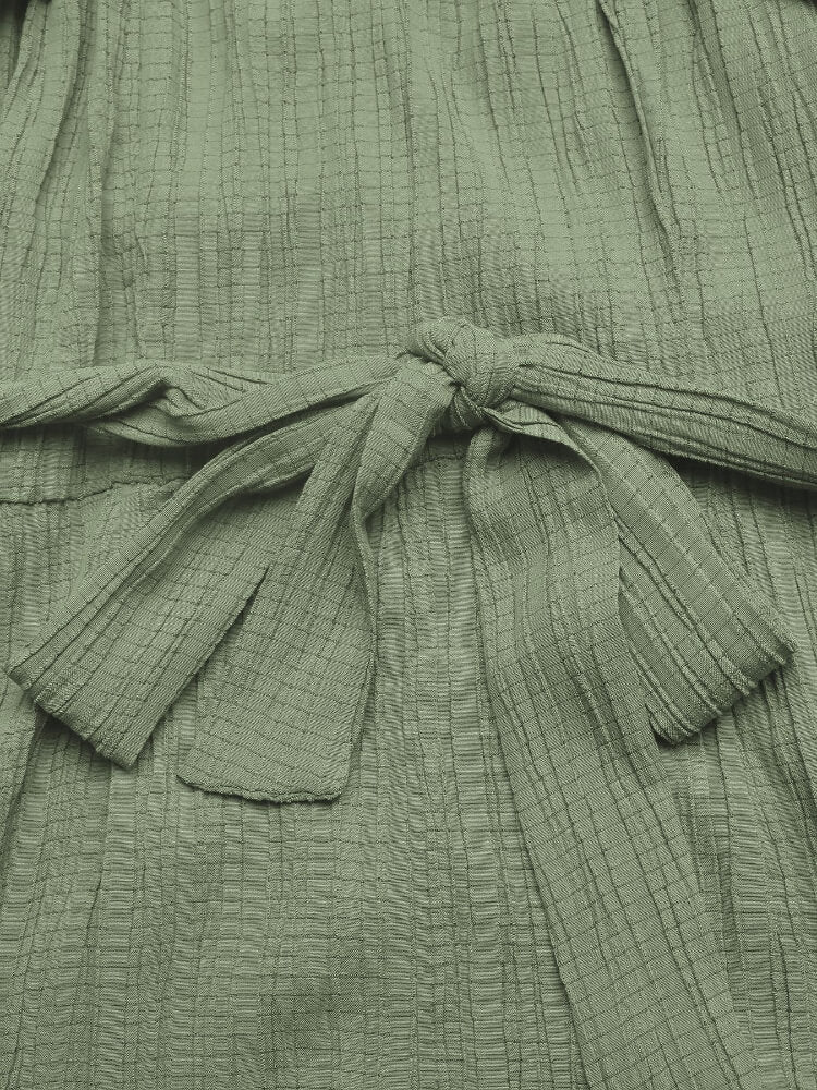 Close-up of a green textured garment with a tie detail.