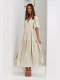 Woman wearing a beige dress with puff sleeves in a minimalistic room.
