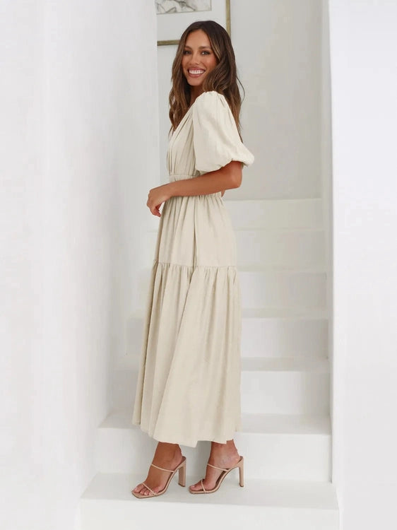 Woman wearing a beige dress standing against a white background