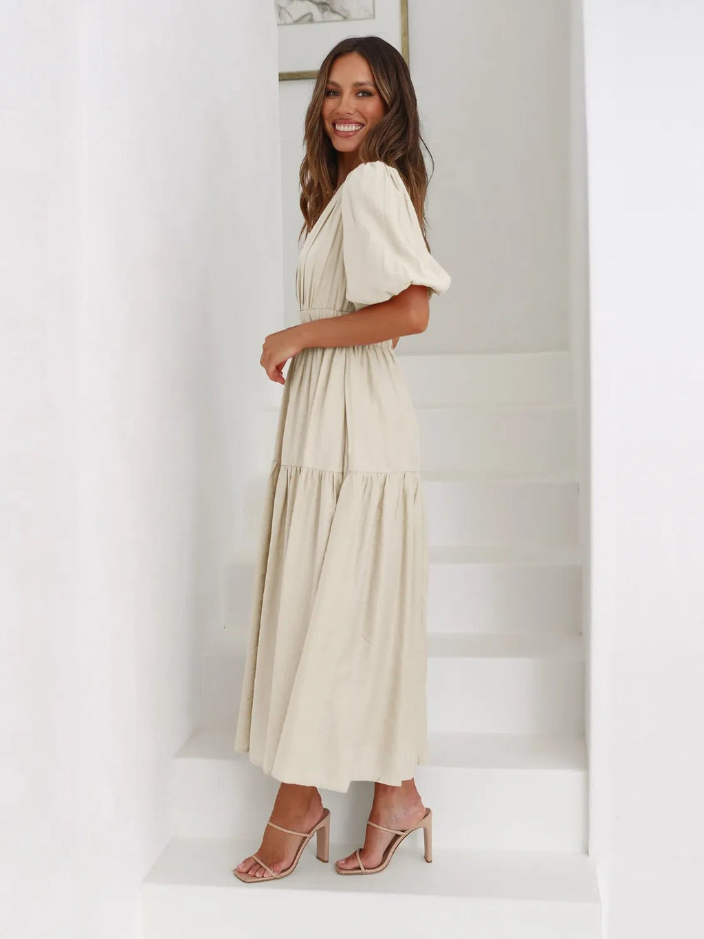Woman wearing a beige dress standing against a white background
