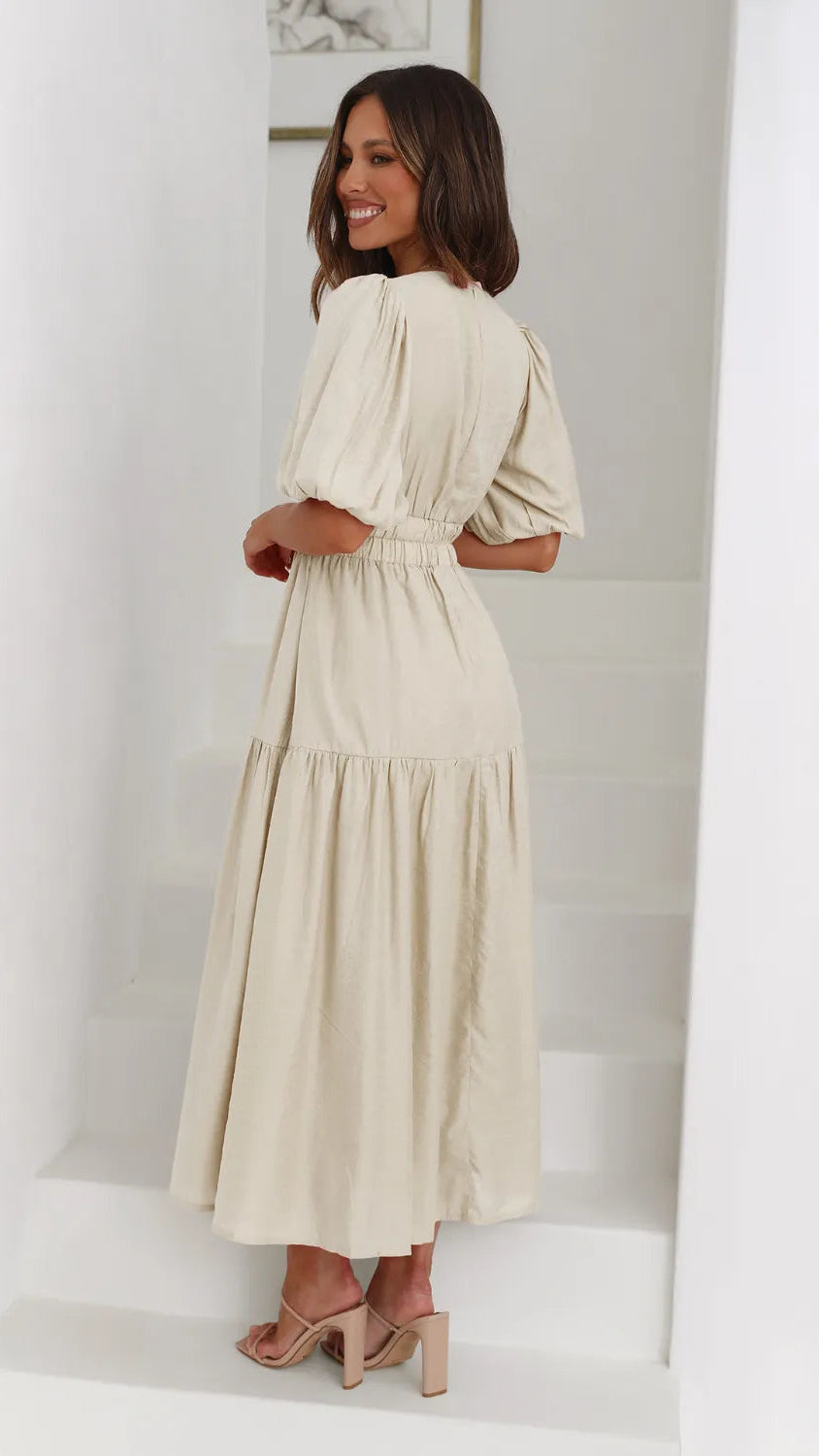 Woman wearing a beige dress in a minimal white room