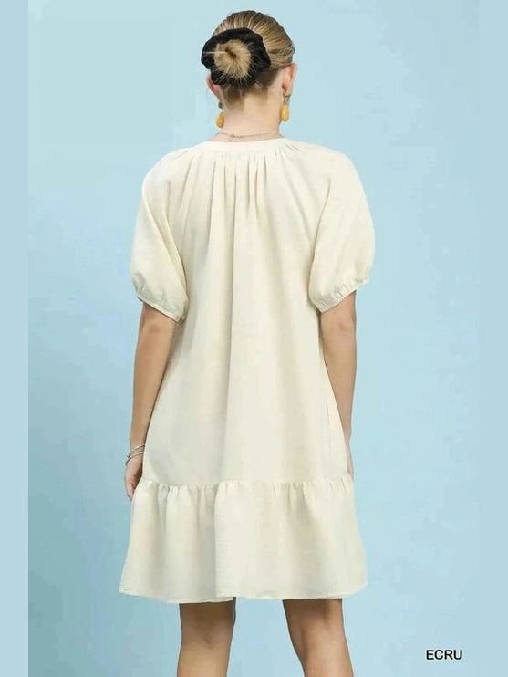 Back detail of cream baby-doll dress featuring gathered neckline pleats