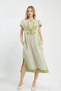 Woman wearing a green and white striped dress with floral embroidery on a white background