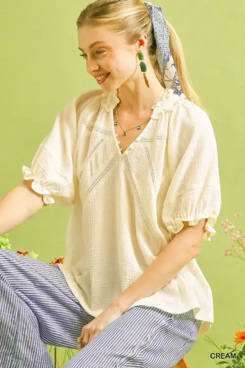 Woman wearing a cream blouse and striped pants against a green background