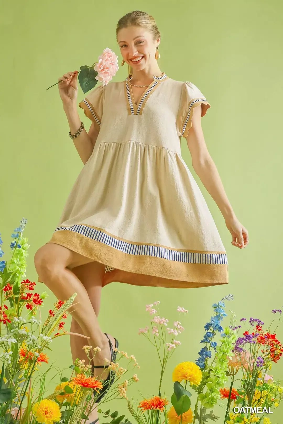 Woman in a beige dress standing among flowers with a green background