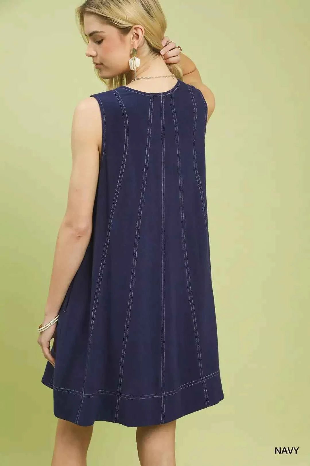 Woman wearing a navy sleeveless dress against a light green background