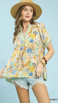 Woman wearing a colorful floral blouse and straw hat on a light blue background