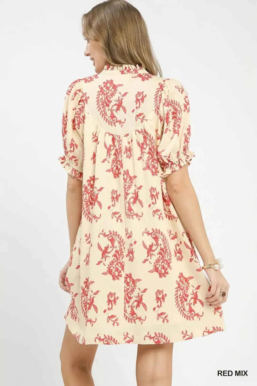 Woman wearing a cream dress with red floral pattern on a white background