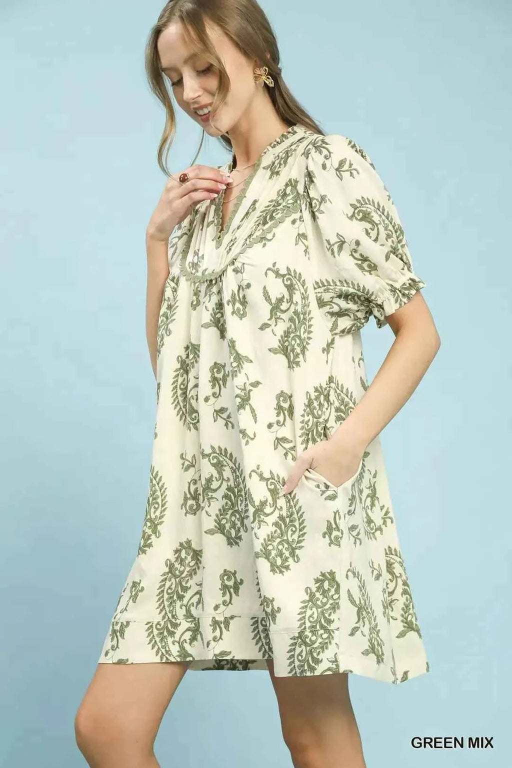 Woman wearing a floral dress against a light blue background laughing