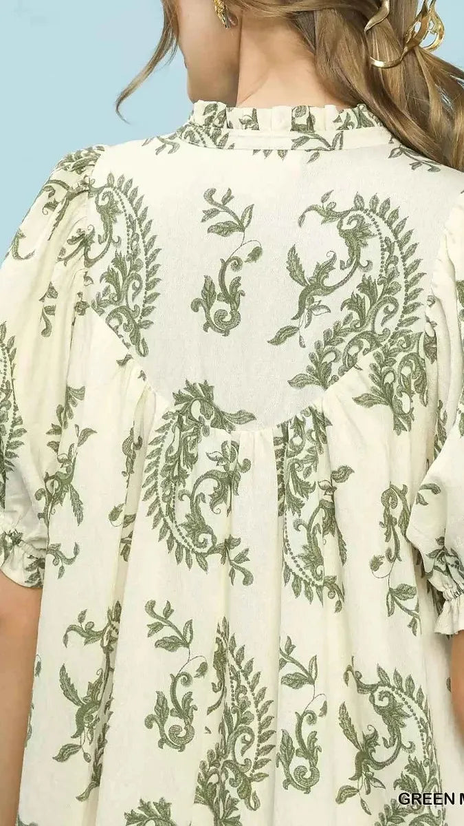White blouse with green floral patterns on a light blue background