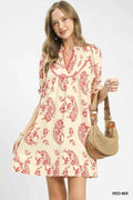 Woman wearing a red and white patterned dress holding a straw bag on a white background