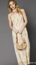 Woman in a floral dress holding a woven bag against a gray background