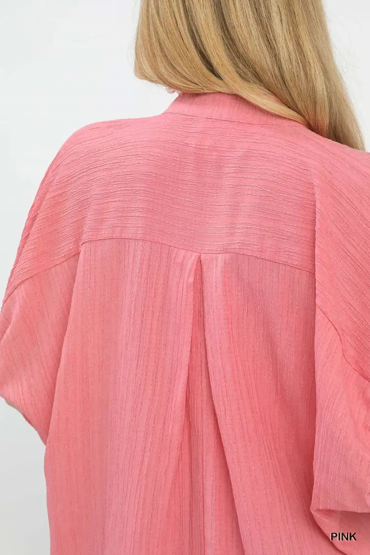 Close-up of a pink textured shirt worn by a person with blonde hair.