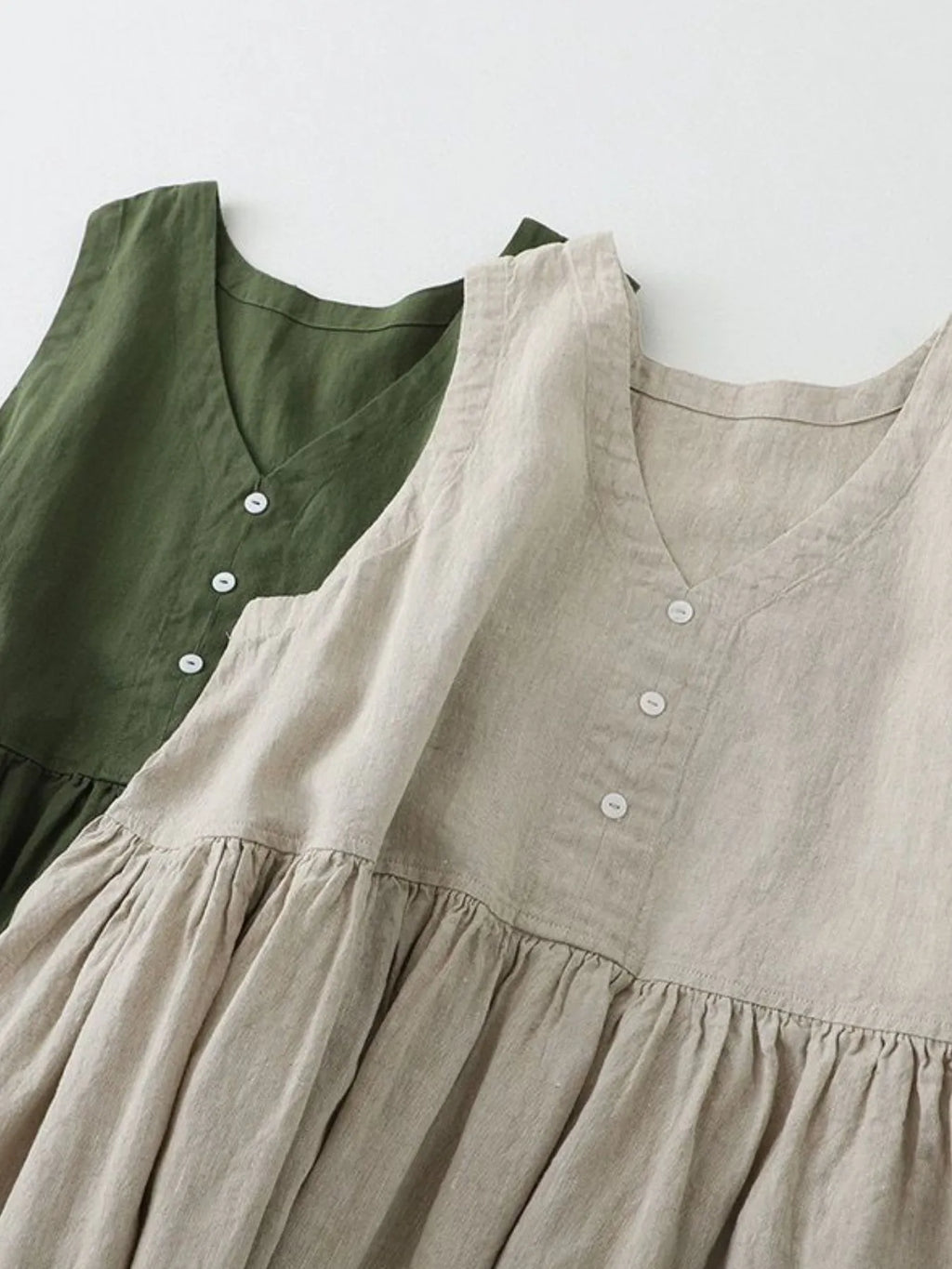 Two dresses, one green and one beige, with a plain background