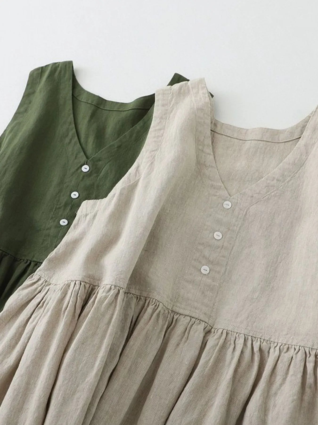 Two dresses, one green and one beige, with a plain background