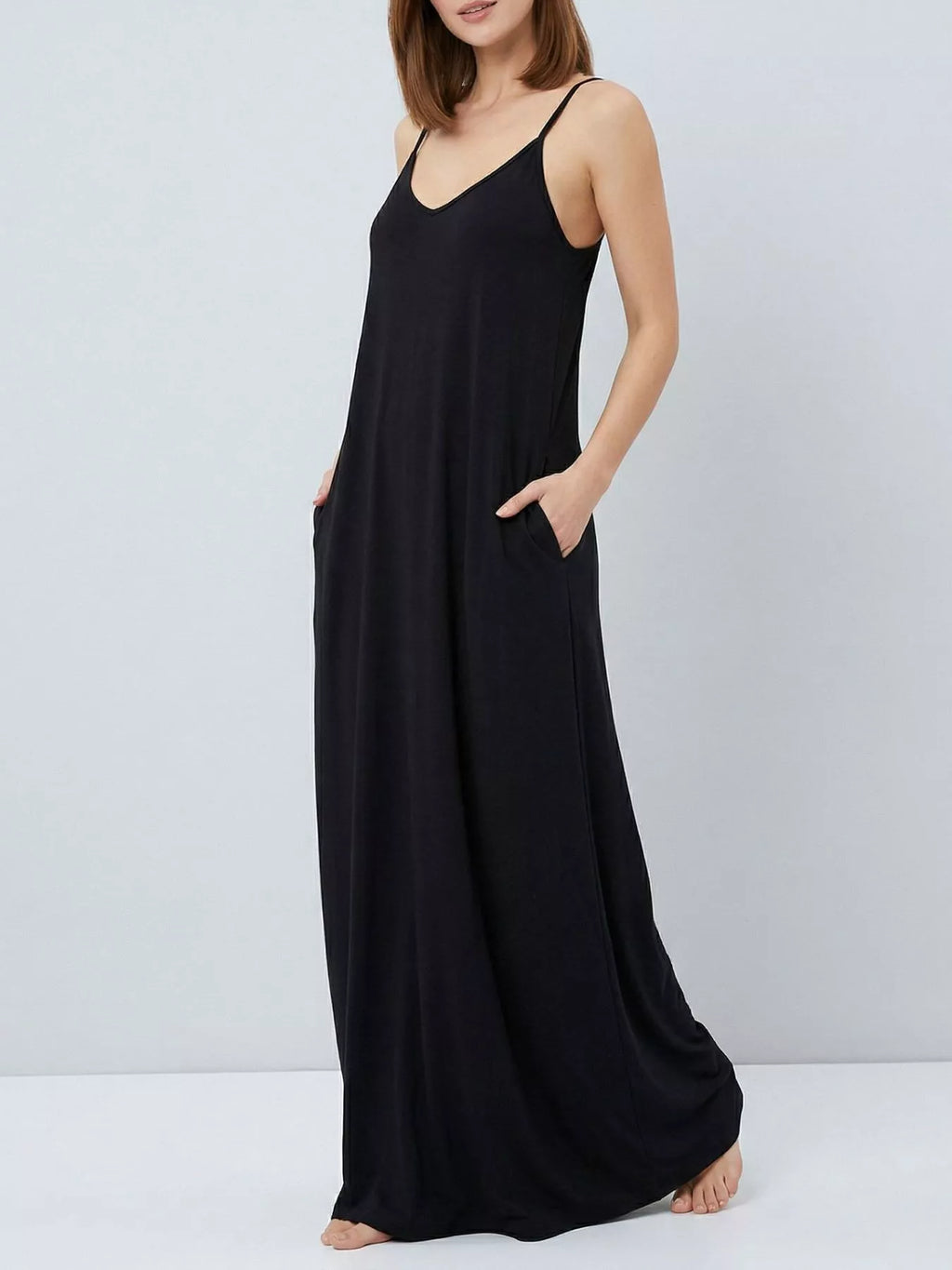 Woman wearing a black slip dress against a plain background