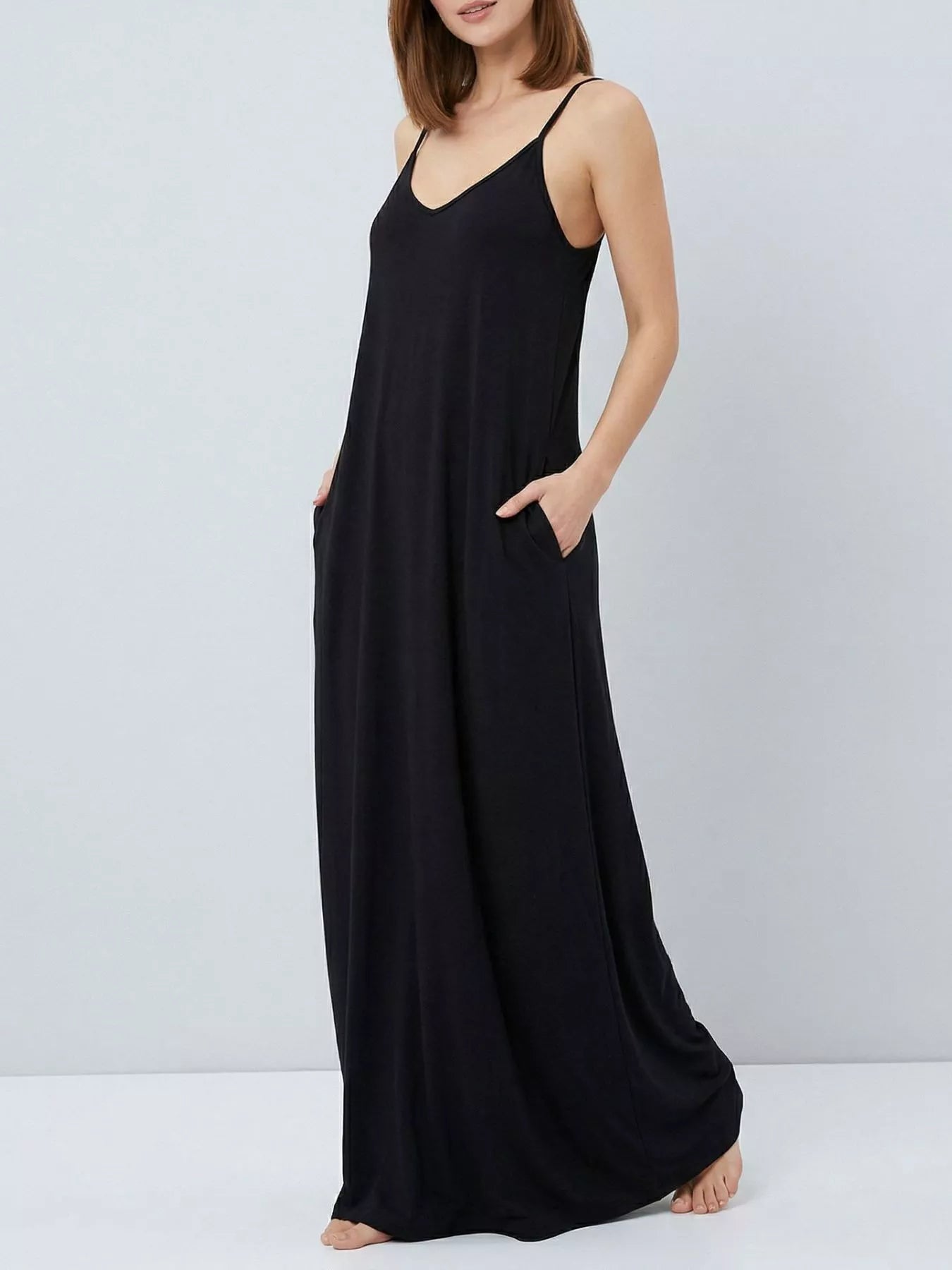 Woman wearing a black slip dress against a plain background