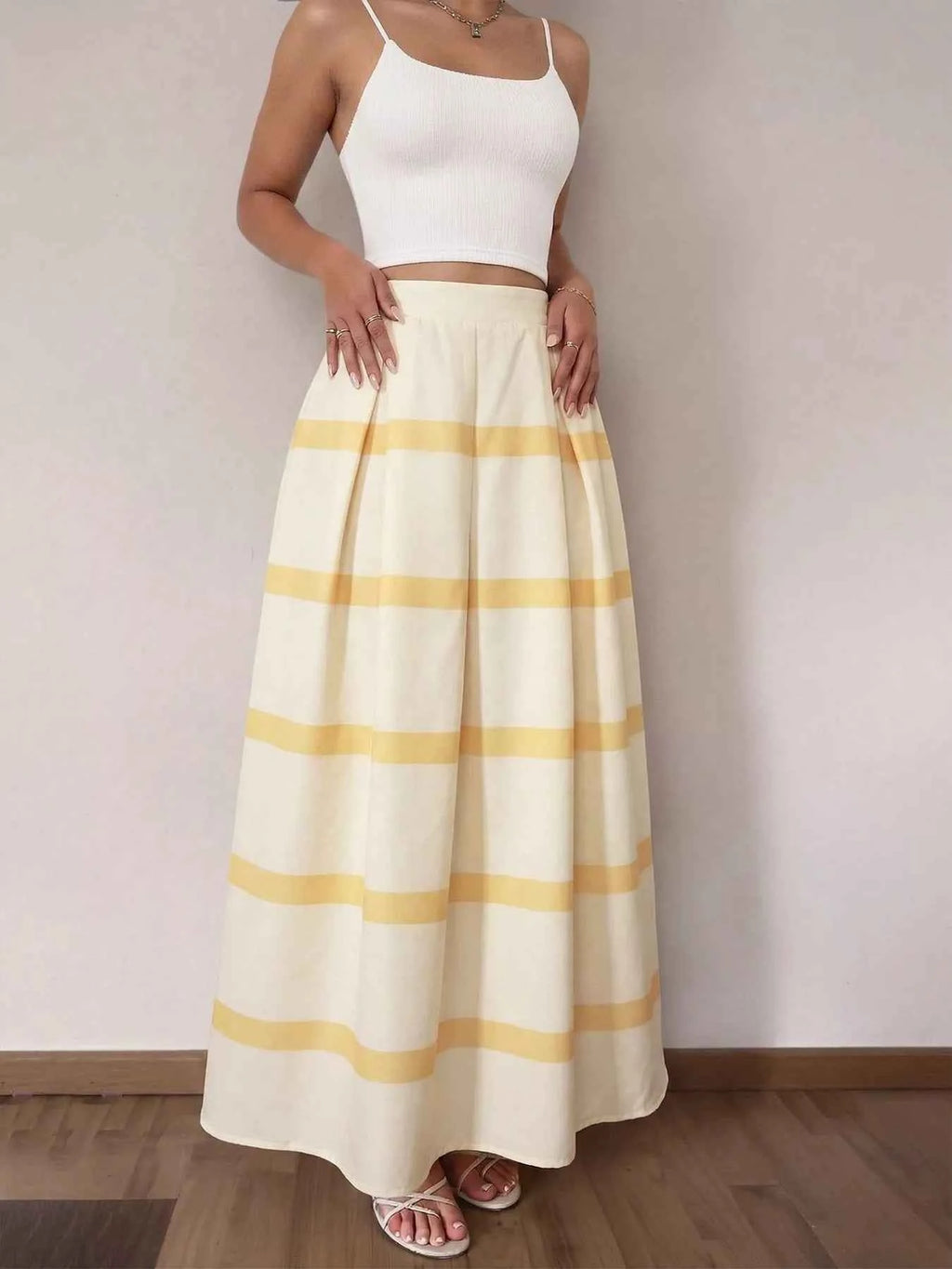 Woman wearing a white top and yellow striped skirt against a plain background