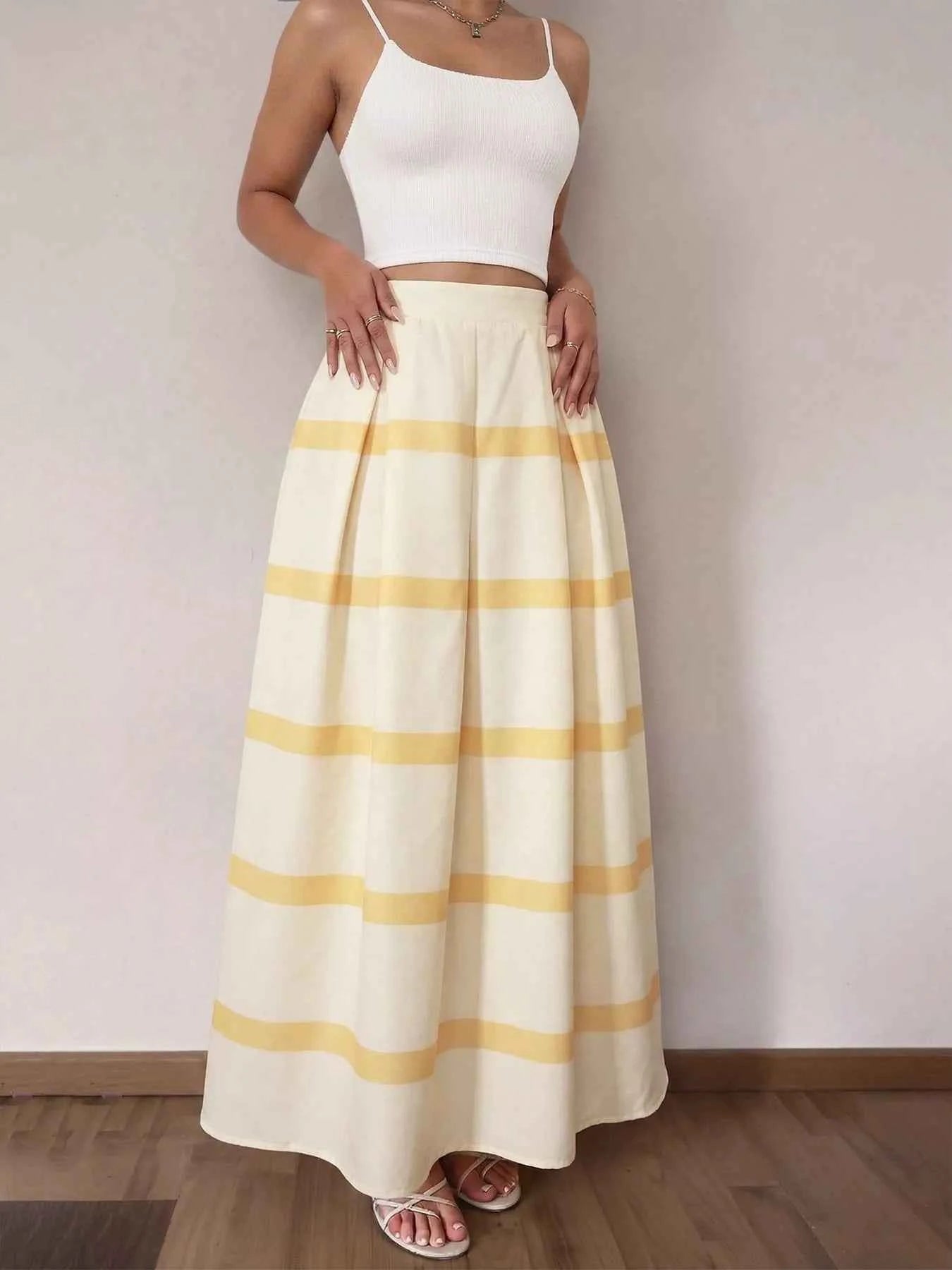 Woman wearing a white top and yellow striped skirt against a plain background