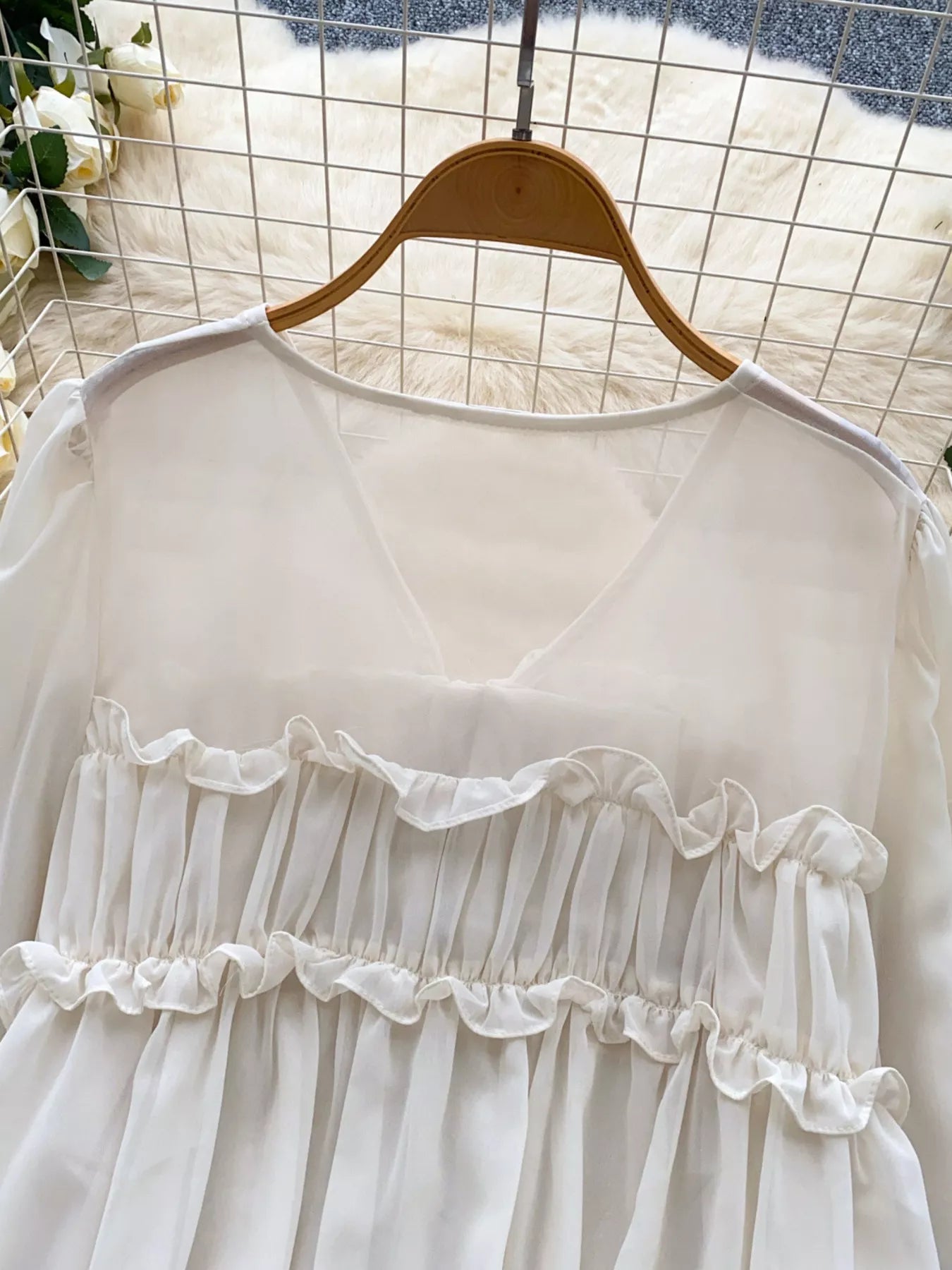White lace-trimmed dress on a hanger against a grid background