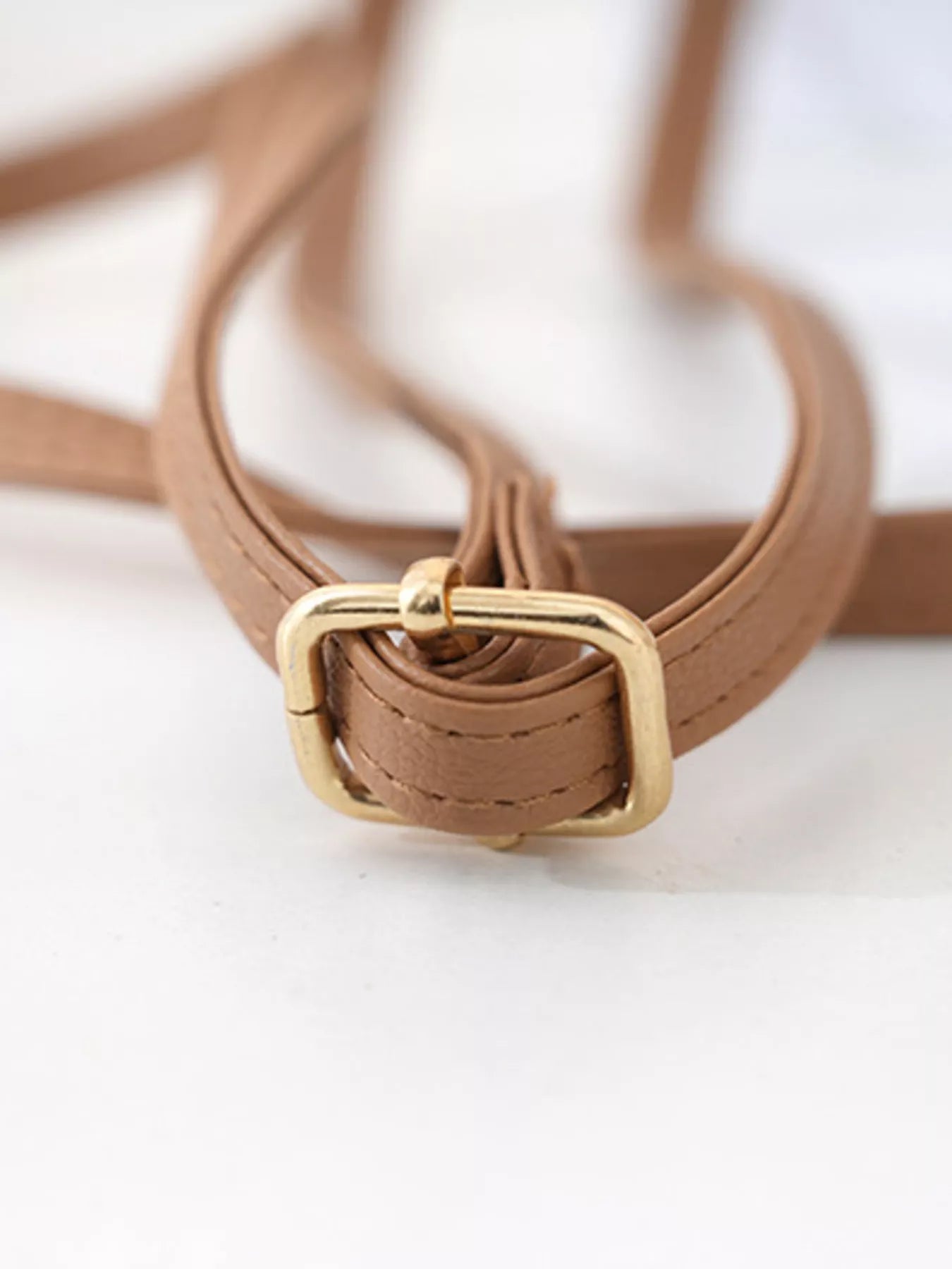 Brown leather belt with a gold buckle on a white background