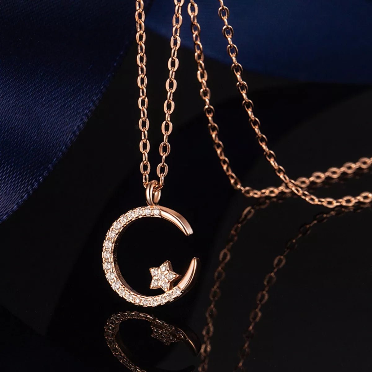 Rose gold necklace with a moon and star pendant on a dark background