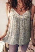 Woman wearing a floral sleeveless top with tattoos on arms, standing against a neutral background.