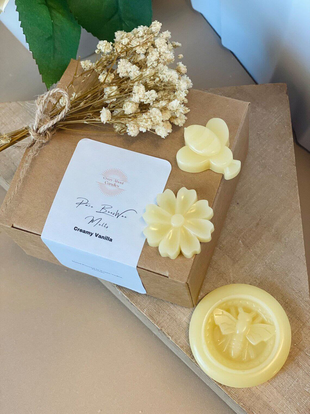 Box of creamy vanilla candles with decorative elements on a wooden surface
