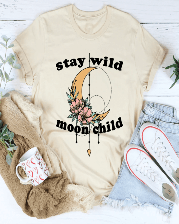 Beige t-shirt with 'stay wild moon child' design, mug, sweater, and jeans on a white background